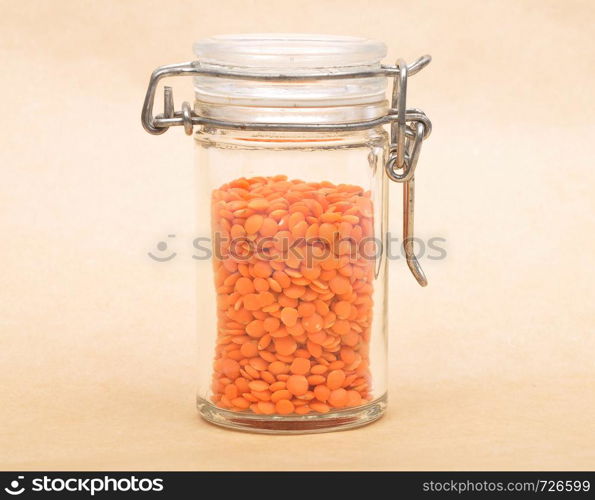 Red lentils in jar and brown background