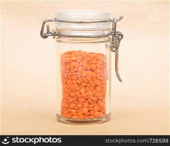 Red lentils in jar and brown background