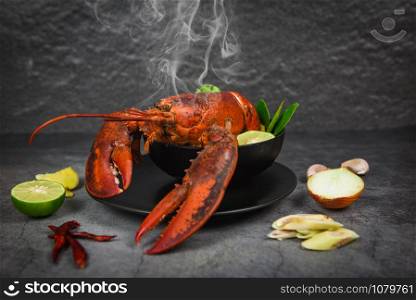 Red lobster spicy soup bowl / Cooked seafood with lobster dinner table and spices ingredients on black plate thai food