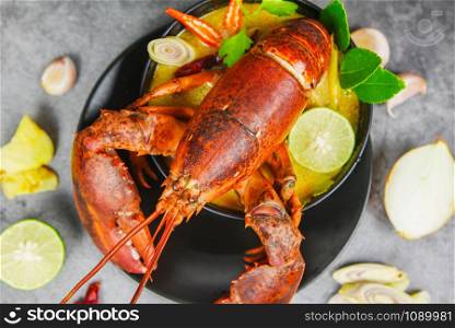 Red lobster spicy soup bowl / Cooked seafood with lobster dinner table and spices ingredients on black plate thai food ,Tom Yum Kung