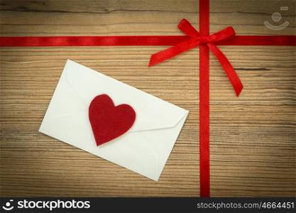Red loop with hearts and white envelope on wooden background