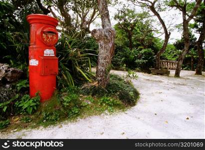 Red mailbox along a walkway, Taketomi, Ryukyus, Japan