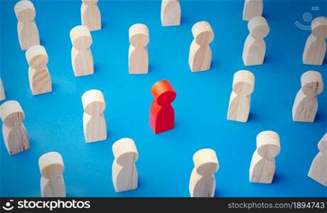 Red man figurine in a people crowd. Stands out from the crowd. Different, special. Collective immunity. Social distance. Intruder detection. A talented and capable candidate. Tolerance in society
