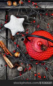 Red metal kettle,branches with berries on wooden background