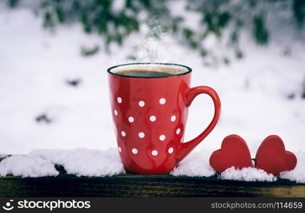 red mug with polka dots with hot black coffee and two wooden hearts, vintage toning