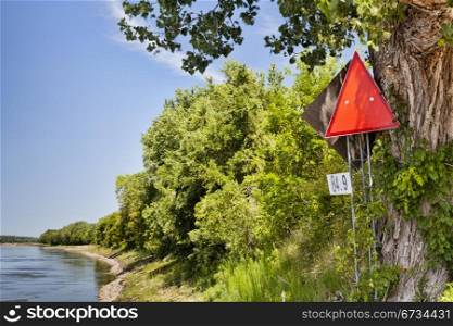 red navigational sign and mileage on left shore of Missouri River