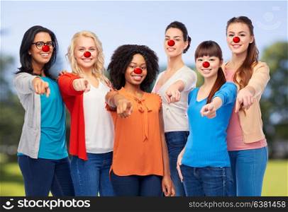 red nose day, diversity and people concept - international group of happy smiling different women with clown noses pointing finger at you over natural background. group of women pointing finger at red nose day