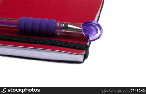 red notebook diary or agenda and purple pen lying on the top (isolated on white background)