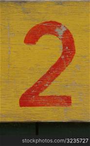 Red number two painted on yellow wood
