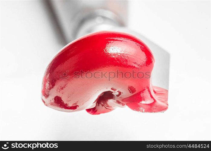 Red oil paint freshly squeezed from the tube sits on the edge of a paint knife.