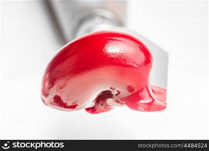 Red oil paint freshly squeezed from the tube sits on the edge of a paint knife.