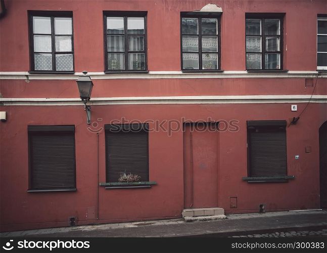 Red old fashioned cafe or shop facade in Vilnius old town with brown rollings