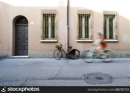 Red old Italian bicycle on sunlight. Ancient buildings