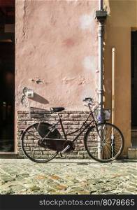 Red old Italian bicycle on sunlight. Ancient buildings