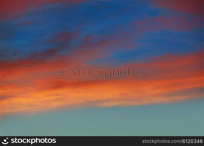 Red orange clouds in dramatic sunset blue sky