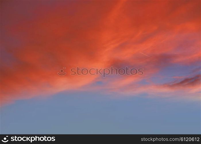 Red orange clouds in dramatic sunset blue sky