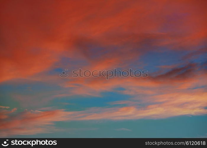 Red orange clouds in dramatic sunset blue sky