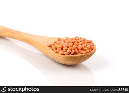 Red organic lentils in wooden spoon isolated on white background