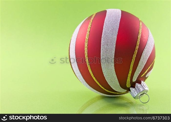 red ornate christmas bauble on green background