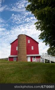 Red painted wooden barn with white door on farm in traditional US style