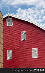 Red painted wooden barn with white door on farm in traditional US style