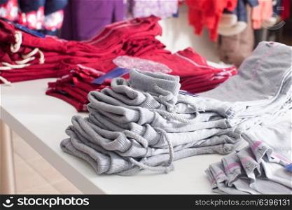 Red pants that stacked in rows on the white shelf in a clothing store. Trendy clothing shop