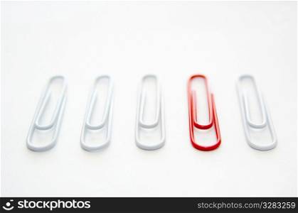 Red paper clip standing out from group of white ones.
