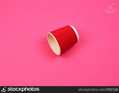red paper cup with corrugated edges for hot drinks on a pink background, copy space