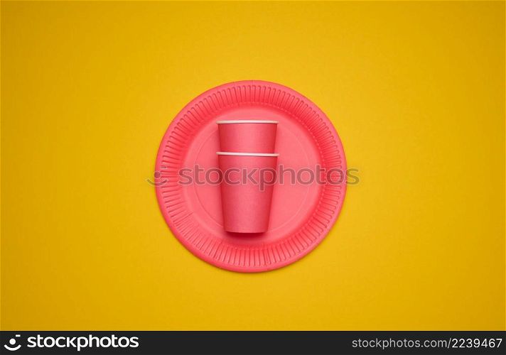 red paper cups and plates on a yellow background. Recyclable garbage, rejection of plastic, top view