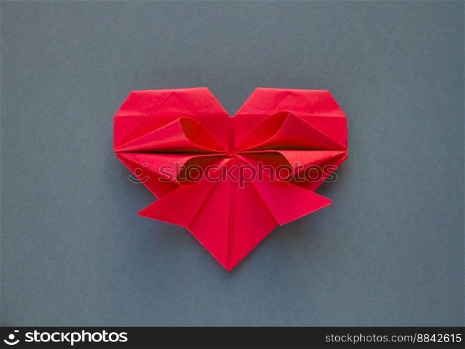Red paper heart origami isolated on a blank grey background. Valentines day card. Red paper heart origami isolated on a grey background