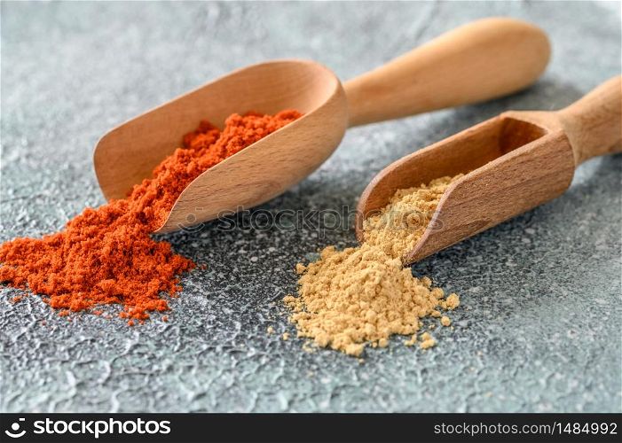 Red paprika and ginger powder in wooden scoop close-up