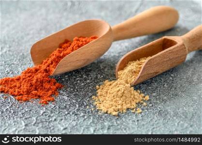 Red paprika and ginger powder in wooden scoop close-up
