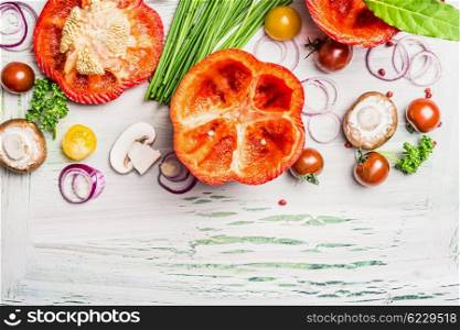 Red paprika with cutting top , ready for stuffing and tasty cooking ingredients on white rustic wooden background, top view, border. Vegetarian food and Healthy eating concept.