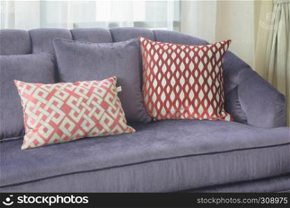 Red pattern pillows lay on violet sofa in living room
