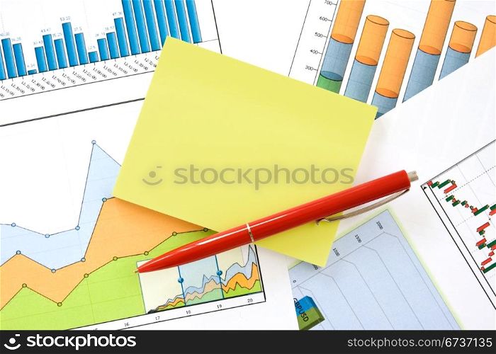 red pen and yellow memo over financial charts