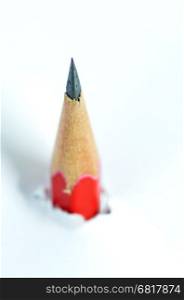 Red pencil going through a white torn paper