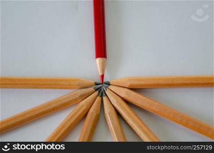 Red pencil standing out from crowd of plenty identical black pencil on white background. Leadership, uniqueness, independence, initiative, strategy, dissent, think different, business success concept