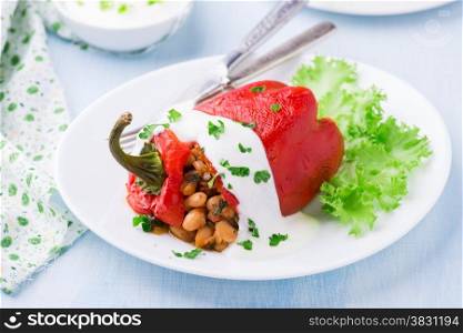 Red pepper stuffed with white beans. Yogurt sauce and green salad. Selective focus. Red pepper stuffed with white beans