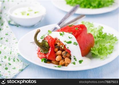 Red pepper stuffed with white beans. Yogurt sauce and green salad. Selective focus