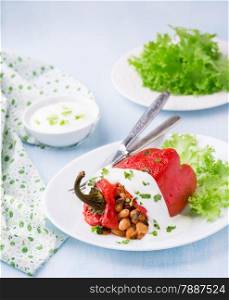 Red pepper stuffed with white beans. Yogurt sauce and green salad. Selective focus. Red pepper stuffed with white beans