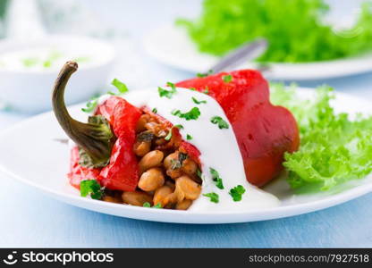 Red pepper stuffed with white beans. Yogurt sauce and green salad. Selective focus