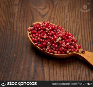 Red peppercorns in a wooden spoon on the table, spice