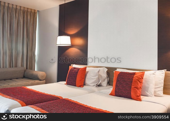 Red pillow on double bedroom with white bedsheet and lamp light on