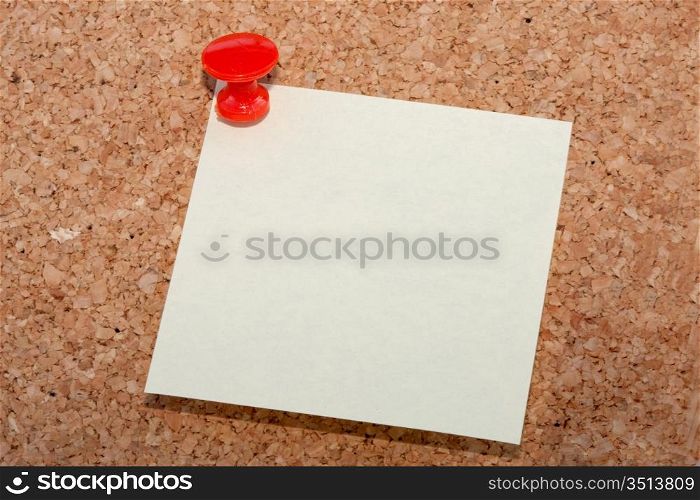 Red pin with note pinned to cork noticeboard