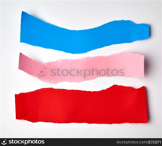 red, pink and blue torn strips of paper on a white background, flat lay