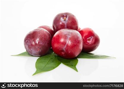 red plum with green leaves isolated on white background