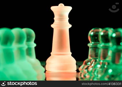 red queen and rows of green glass chess pieces is standing on board in dark