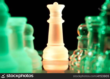 red queen and rows of green glass chess pieces is standing on board in dark