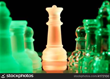 red queen and rows of green glass chess pieces is standing on board in dark