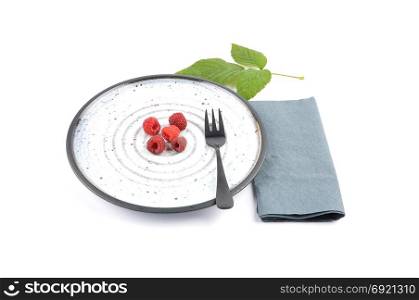 Red raspberries on plate and white